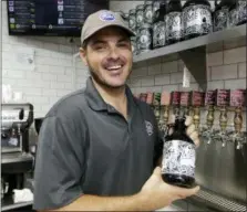  ?? AP PHOTOS/LYNNE SLADKY ?? Manager Andrew Mendez holds a beer growler for craft beer sold at the Mendez Fuel convenienc­e store in Miami. In convenienc­e stores spawned by the wellness wave, kombucha slushies take the place of corn-syrupy treats infused with red dye, tortilla chips are made of cassava flour instead of corn, and there are vegan ice cream bars, a dizzying selection of organic produce and craft beer on tap.