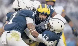  ?? SCOTT TAETSCH/GETTY ?? Michigan’s Erick All, center, carries the ball with Penn State’s Ellis Brooks, right, Jaquan Brisker, left, and Arnold Ebiketie trying to take him down Saturday.