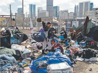  ?? RJ Sangosti, The Denver Post ?? A homeless woman hurries to get her belongings moments before Denver police officers and public works crews began clearing homeless camps near Samaritan House in downtown Denver on March 8, 2016. The city has struggled with how to handle camps, and now provides advance warning before removing any items left on public sidewalks or other public property.