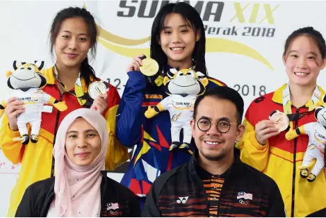  ??  ?? One for the album: Nurul Izzah Anwar (Permatang Pauh MP) and Deputy Youth and Sports Minister Steven Sim (front right) posing with 3m springboar­d gold medallist Loh Zhiayi (back, centre), silver medallist Adeline Chin (back, left) and third-place Koh Hui Yan at the Tuanku Zara Aquatic Centre yesterday.