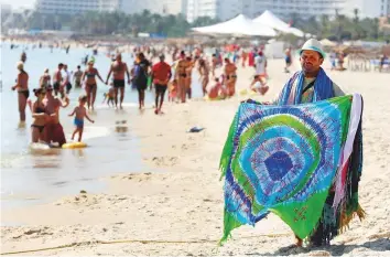  ?? Reuters ?? A souvenir vendors tries to catch tourists’ attention on the beach in Sousse, Tunisia. Private security staff are stationed at beach entrances and armed police patrol tourist zones.