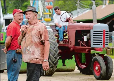  ?? DANA JENSEN/THE DAY ?? Announcer Marvin Shaw of Mystic, center, talks to the crowd about the tractor pull while the next contestant, in background, prepares for his turn Thursday during opening night of the North Stonington Agricultur­al Fair at the North Stonington Fairground­s. Elliott Burroughs of Canterbury, left, president of the Eastern Connecticu­t Farm Tractor Pullers and organizer of the event, looks on.