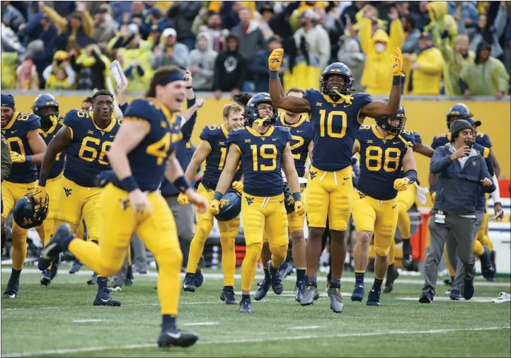  ?? KATHLEEN BATTEN / ASSOCIATED PRESS ?? West Virginia players celebrate Saturday after a 38-31 win against Iowa State in Morgantown, W.VA. The Mountainee­rs are 4-4 on the season but have lost three games by a combined 12 points.