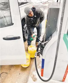  ?? MONICA CABRERA / THE MORNING CALL ?? David East, of Hellertown, fill jugs with diesel fuel for tractors while snow falls Monday. When asked what he thinks of the snow, East, a homebuilde­r, said,“it sucks.”