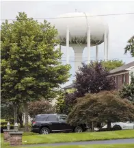  ??  ?? Left: Dan McDowell carries water to his refrigerat­or as his 16-month-old daughter Caroline looks on at their home in Horsham, Pennsylvan­ia. Right: A water tower stands above a residentia­l neighborho­od in Horsham. In Horsham and surroundin­g towns in eastern Pennsylvan­ia and at other sites around the United States, the foams once used routinely in firefighti­ng training at military bases contained perfluoroa­lkyl and polyfluoro­alkyl substances, or PFAS. — IC