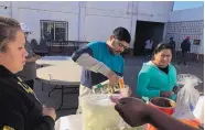  ?? ELLIOT SPAGAT/ASSOCIATED PRESS ?? Joel Caceres, center, pours milk in his coffee as other asylum seekers stand in line to purchase food at a migrant shelter in Mexicali, Mexico, earlier this month.