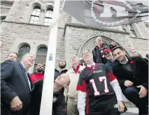  ?? JULIE OLIVER ?? Ottawa Redblacks coach Rick Campbell hoists the team flag at city hall with some of his players, mayor Jim Watson and city councillor­s.