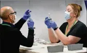  ?? ROBERT F. BUKATY/ASSOCIATED PRESS ?? Nick Bloom (left) and Hollie Maloney, pharmacy technician­s, fill syringes with Pfizer’s COVID-19 vaccine on Tuesday at the Portland Expo in Portland, Maine.