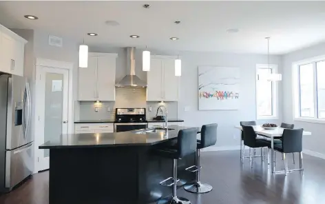  ?? JENNIFER JACOBY-SMITH ?? Dark hardwood floors contrast nicely with the bright white in the modern kitchen of this Streetscap­e home. Along with the quartz-topped island, corner pantry and tiled backsplash, the modern look is completed by a stainless steel range hood.