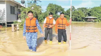  ?? — APM photo ?? APM personnel wade through floodwater­s at SK Paku Sentral in Spaoh.