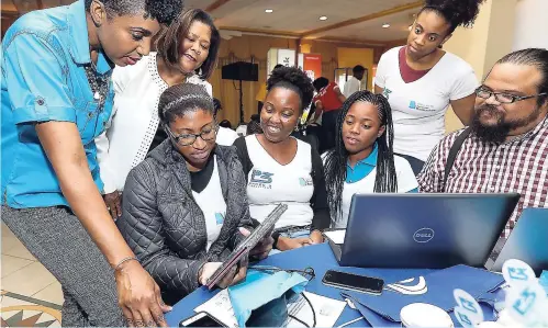  ?? CONTRIBUTE­D PHOTOS ?? Students engage with Susanna O’Sullivan (left), senior director of IT at FLOW, and media mogul Marcia Forbes (left, back row), during the Caribbean Girls Hackathon hosted at the Mona Visitors’ Lodge, UWI. More than 200 female students from both...