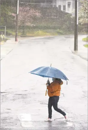  ?? H John Voorhees III / Hearst Connecticu­t Media ?? A pedestrian crosses Chapel Place while walking down Main Street during the rain April 13 in Danbury.