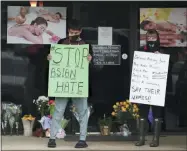  ?? CURTIS COMPTON—ASSOCIATED PRESS ?? After dropping off flowers Jesus Estrella, left, and Shelby stand in support of the Asian and Hispanic community outside Young’s Asian Massage Wednesday, March 17, 2021, in Acworth, Ga. Asian Americans, already worn down by a year of racist attacks fueled by the pandemic, are reeling but trying to find a path forward in the wake of the horrific shootings at three Atlanta-area massage businesses that left eight people dead, most of them Asian women.