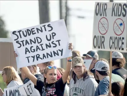  ?? Pam Panchak/Post-Gazette ?? Lily Silvis, 15, a sophomore at Hempfield Area High School, holds up a sign Tuesday as she stands with a group of students and parents in front of the school in Greensburg protesting the statewide policy requiring masks to be worn in schools. Ms. Silvis helped organize the protest.