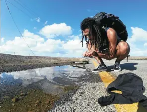  ??  ?? This adventurer took water wherever he found it, even from a puddle in South Africa.