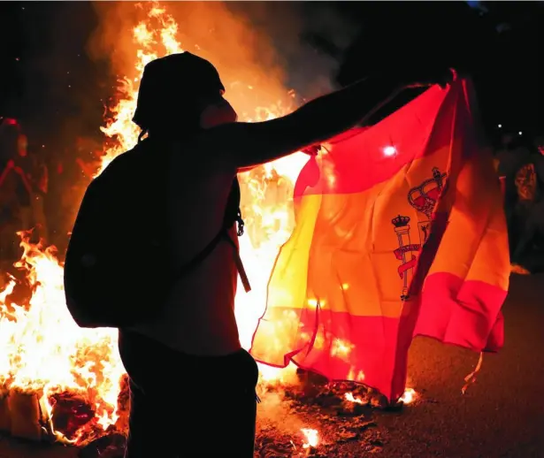  ?? REUTERS ?? Manifestan­te independen­tista con una bandera española junto a una hoguera durante la última Diada en Barcelona