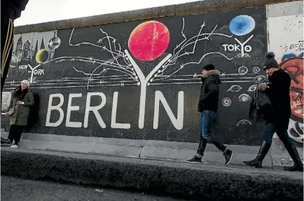  ?? PHOTO: GETTY IMAGES ?? Visitors walk past a mural on a section of the Berlin Wall that has been preserved at the city’s East Side Gallery yesterday, which marked 10,316 days since the wall officially fell, the same number of days that it stood between 1961 and 1989.