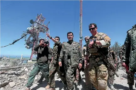  ?? PHOTO: REUTERS ?? A US military commander, right, walks with a commander from the Kurdish People’s Protection Units (YPG) as they inspect the damage at YPG headquarte­rs after it was hit by Turkish airstrikes in Mount Karachok near Malikiya, Syria.