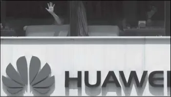  ?? Associated Press ?? A man presses on the glass window Thursday near a logo for Huawei in Beijing.