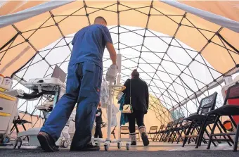  ?? HAYNE PALMOUR IV/SAN DIEGO UNION-TRIBUNE ?? A woman suffering from flu symptoms, right, walks into a tent outside of the Palomar Medical Center Escondido so that medical staff members can triage the flu patients on Wednesday in Escondido, Calif.