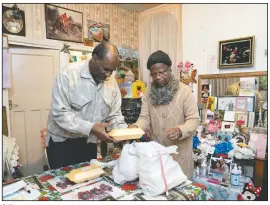  ??  ?? Sylius (left) and Bridgette Toussaint unpack their meals prepared by members of the Preston Windrush Covid Response team in Preston, England.