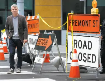  ?? Paul Chinn / The Chronicle ?? Andrew Robinson, executive director of the East Cut Community Benefit District, walks across Fremont Street. The block that runs under the transit center remains closed to traffic.