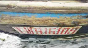  ??  ?? Numbers and letters are seen on a wooden boat containing human remains and suspected to be from North Korea, according to a Coast Guard official, along a shore of Sado island, Japan.