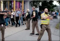  ??  ?? Shoppers are escorted from the Olympia mall (left) in Munich after Friday’s shooting. At right, officers take position outside the mall hours before officials gave a “cautious all clear” when the gunman’s body was found.
