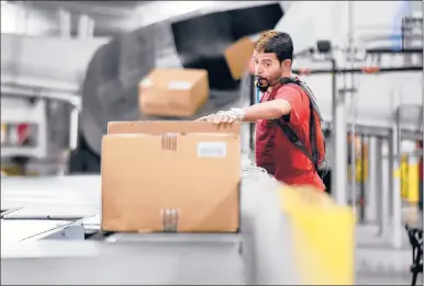  ?? CLOE POISSON | CPOISSON@COURANT.COM ?? JOSELITO MARTINEZ, of Middletown, positions packages so their labels can be read by a scanner as they move down a conveyor belt at the new Fed Ex Ground hub in Middletown, where he works as a “facer.” The grand opening for the facility took place Friday with a ribbon-cutting ceremony and tours of the 600,000-square-foot building on the former Aetna site on Middle Street. The hub features 18 miles of conveyor belts.