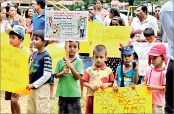  ??  ?? Children hold placards which appeal to President Mahinda Rajapaksa not to take over the land