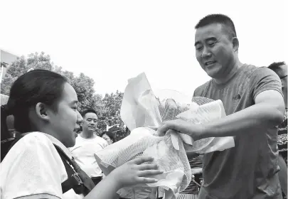  ??  ?? Zhang Yilin (left), who has limited leg and arm movement, presents a bunch of flowers to teacher Zhou Aifeng at Minhang Experiment­al Primary School yesterday in thanks for his help. — Dong Jun