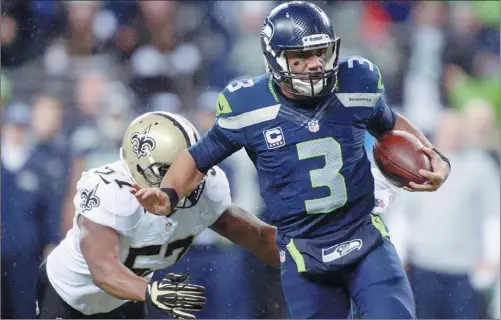  ?? KIRBY LEE / USA TODAY SPORTS ?? Seattle Seahawks quarterbac­k Russell Wilson eludes New Orleans Saints linebacker David Hawthorne at CenturyLin­k Field in Seattle on Monday.