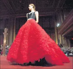  ?? Angela Weiss AFP/Getty Images ?? THIS GOWN worthy of any red carpet paired a tight black bodice with cascading red tulle that resembled a gigantic wearable bouquet of roses.