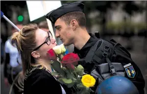  ?? AP/EMILIO MORENATTI ?? A woman kisses a French police officer after giving him flowers Saturday near the Eiffel Tower in Paris during a demonstrat­ion of support for French security forces on guard for the election.