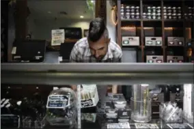  ?? THE ASSOCIATED PRESS ?? In this June 27 photo, Jerred Kiloh, owner of the Higher Path medical marijuana dispensary, stocks shelves with with cannabis products in Los Angeles.