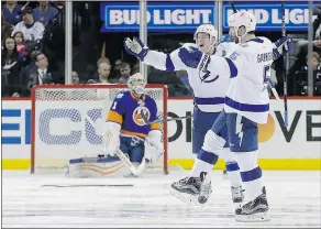  ?? — THE ASSOCIATED PRESS ?? After an overtime victory over the Islanders Friday, Jason Garrison, right, and the Lightning are a win away from a second straight trip to the Eastern Conference final.