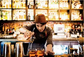  ??  ?? DINERS GATHER at long beer-garden-style tables at Federalist Public House in Midtown Sacramento, top. Luis Ledezma makes Old Fashioned cocktails at the Block Butcher Bar at LowBrau in Midtown.