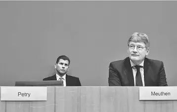  ??  ?? Joerg Meuthen (right), co-leader of Germany’s nationalis­t Alternativ­e for Germany (AfD) party, sits next to the empty seat of AfD co-leader Frauke Petry as the party’s spokesman Christian Lueth (in the background) looks on during a press conference in...