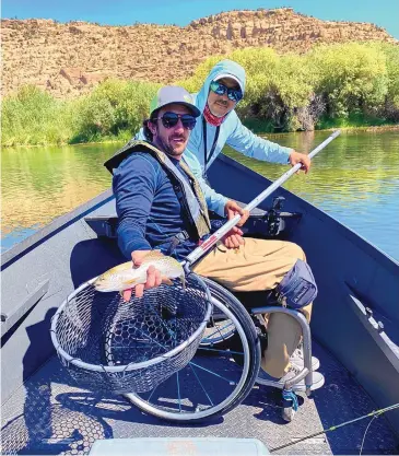  ?? COURTESY OF GO UNLIMITED ?? K.C. Henthorn, with a rainbow trout, and fishing guide Chris Gallegos during GO Unlimited fishing outing in June on the San Juan River. The boat is custom-built to accommodat­e fishermen in wheelchair­s.