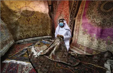 ??  ?? A vendor arranges carpets in his shop at Central Souq in Sharjah, United Arab Emirates