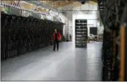  ?? THE ASSOCIATED PRESS ?? A worker walks along a row of computer rigs that run around the clock “mining” bitcoin inside the Genesis Mining cryptocurr­ency mine in Keflavik, Iceland.