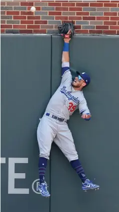  ?? Curtis Compton/Atlanta Journal-Constituti­on via AP ?? ■ Los Angeles Dodgers’ Cody Bellinger just misses a ball hit by Atlanta Braves’ Ronald Acuna Jr. that dropped inside the park Sunday during the third inning in Atlanta, Ga. Acuna Jr. was pulled from the game by manager Brian Snitker for not running out the play.