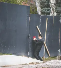  ?? PETER J THOMPSON / NATIONAL POST ?? A reporter takes a photo through a hole in a wall around Honey and Barry Sherman’s property at 50 Old Colony Road in Toronto.