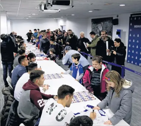  ??  ?? UNA FIRMA, UNA ILUSIÓN. Los jugadores del Espanyol, a un lado de la mesa, le firman autógrafos a los más pequeños en Cornellà.