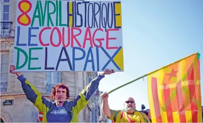  ?? AFP ?? A man holds a placard that reads ‘Historic 8th of April. The Courage of Peace”, next to another man with Basque and Catalan flags, following the confirmati­on of disarmamen­t by Basque separatist­s ETA in Bayonne. —