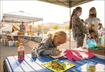  ??  ?? CHEYENNE BREWER, 7, colors at a Home Depot donation center in Phoenix. Soaring rent in the Bay Area led her mom, Shannon King, to move to Oregon. Last week, the family fled the fire; their mobile home is gone.