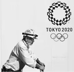  ??  ?? A constructi­on worker walks past at a constructi­on site of a building displaying Tokyo 2020 Olympics emblem in Tokyo, Japan in this May 23 file photo. — Reuters photo