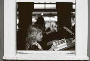  ?? Billy Calzada / Staff photograph­er ?? Willa Walter reads through an old book while sitting in a one-room schoolhous­e during the Texas Folklife Festival on the grounds of the Institute of Texan Cultures.