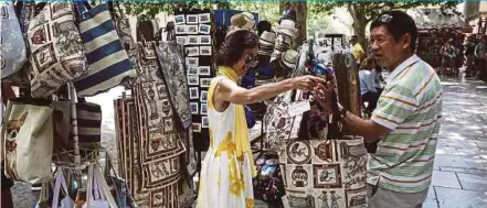  ?? BLOOMBERG PIC ?? Chinese tourists at a souvenir shop in Athens. China is the world’s biggest market for foreign tourism, with 129 million holidaymak­ers travelling abroad.