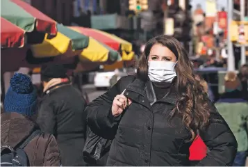  ?? MARK LENNIHAN/ASSOCIATED PRESS ?? A woman, who declined to give her name but says she works for a pharmaceut­ical company, wears a mask last month in New York. She said she wears the mask out of concern for the coronaviru­s. On Tuesday, federal health officials warned that the COVID-19 virus will almost certainly spread in the United States.